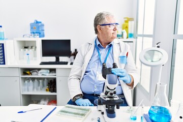 Fototapeta premium Senior caucasian man working at scientist laboratory looking to side, relax profile pose with natural face and confident smile.