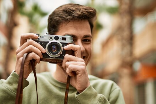 Young hispanic tourist man smiling happy using vintage camera at the city.