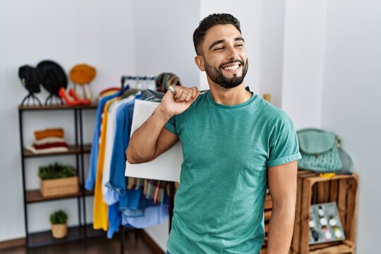 Young Handsome Man With Beard Holding Shopping Bags At Retail Shop Looking Away To Side With Smile On Face, Natural Expression. Laughing Confident.