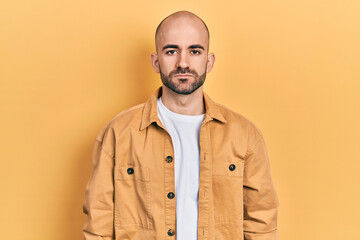 Young bald man wearing casual clothes with serious expression on face. simple and natural looking at the camera.