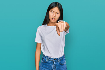 Beautiful young asian woman wearing casual white t shirt pointing displeased and frustrated to the camera, angry and furious with you