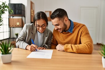 Couple smiling happy reading document at the office.