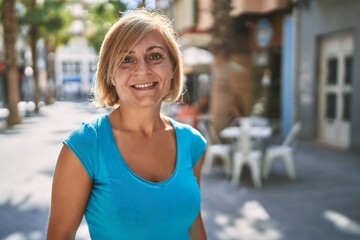 Middle age beautiful woman smiling confident at street