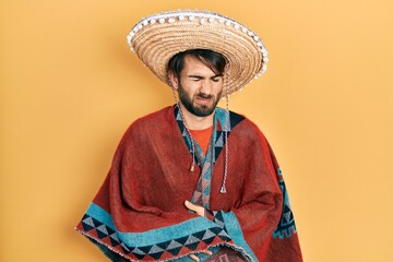 Young hispanic man holding mexican hat with hand on stomach because indigestion, painful illness...