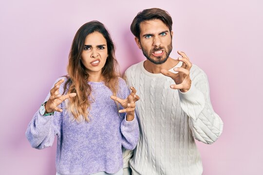 Young hispanic couple wearing casual clothes shouting frustrated with rage, hands trying to strangle, yelling mad