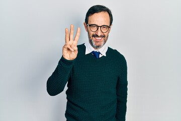 Middle age hispanic man wearing casual clothes and glasses showing and pointing up with fingers number three while smiling confident and happy.