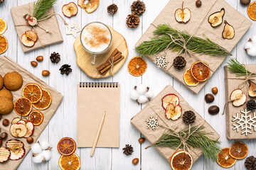 
Gift boxes wrapped reusable craft paper, decorated dried fruits, pine cones, fir branches and blank spiral notebook. Zero wast Christmas composition. Trendy branding mock up. New year gifts mockup.