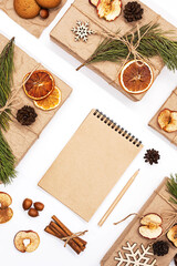 
Gift boxes wrapped reusable craft paper, decorated dried fruits, pine cones, fir branches and blank spiral notebook. Zero wast Christmas composition. Trendy branding mock up. New year gifts mockup.