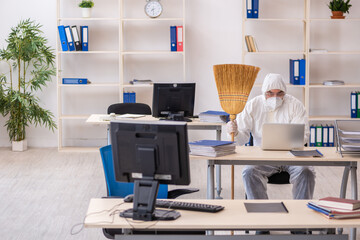 Old male contractor cleaning the office holding broom