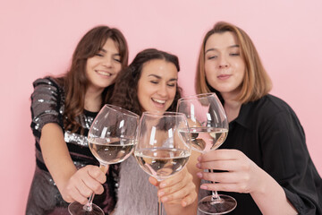 The company of girls with glasses of champagne on a pink background.