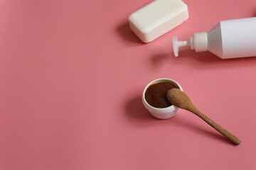 Spa composition with scrub, means with dispenser and soap on a pink background.