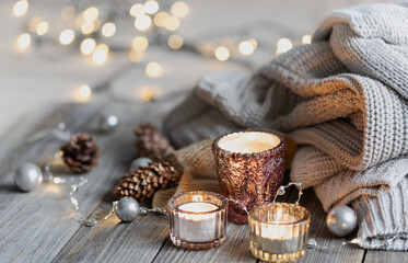 Cozy winter composition with burning candles on a blurred background with bokeh.