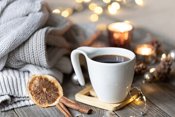 Cup of tea on a blurred background with candles, knitted sweaters, and bokeh.