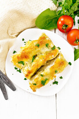 Cannelloni with curd and spinach in plate on board top