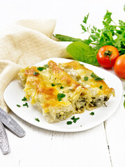 Cannelloni with curd and spinach in plate on wooden board