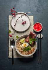 Asian noodle soup, ramen with meat, vegetables and egg top view on black background closeup. Selective focus