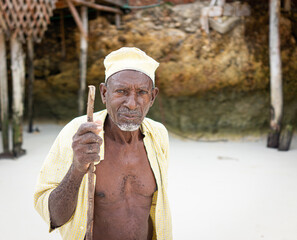 Aged African shepard walking on the beach holding stick