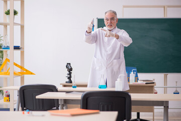 Old male chemist teacher in the classroom