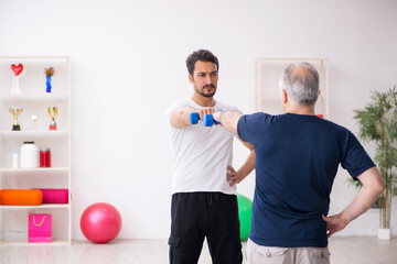 Young male instructor and old man doing sport exercises