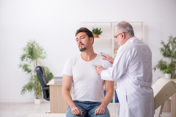 Obraz premium Young male patient visiting old male doctor