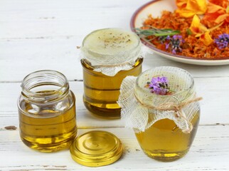 Natural oil from medicinal herbs after filtering in a jar.  Homemade curative oil good for the skin on white table.