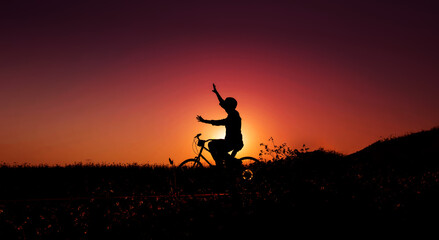 Fototapeta na wymiar Balance, Enjoying Life and Harmony Concept. Silhouette of Happiness Person on Bicycle with raised arms to Balancing Body during Sunrise or Sunset