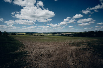 Springtime farmers field in the Britain, blue sky and clouds, with grass, looking out on a horizon