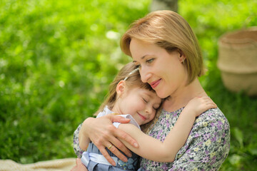 Side view close up head shot happy cute daughter hugging embracing cuddling mother. Concept of happy family. Portrait happy smiling child hugging mother in summer day