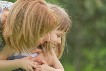 Side view close up head shot happy mom hugs her little daughter, photo in motion, soft focus, love and support. Concept of happy family