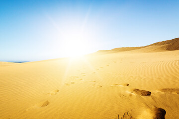 Blue sky and sand dunes with footprints.