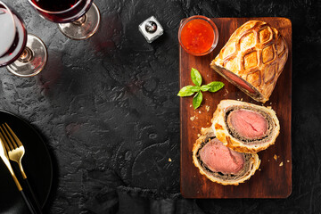 Beef Wellington - beef tenderloin festive dish. English cuisine. Black stone background. top view