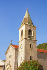 Fototapeta na wymiar Religious architecture. Bell tower of ancient Catholic Church of Saint Roch ( St Roko ). Montenegro, Tivat. Donja Lastva village