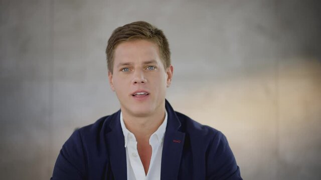 Young adult man looking at camera and talking. Fit of laughter during video call. Online communication.