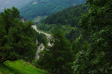Fototapeta na wymiar long curvy highway through the green mountains view from above