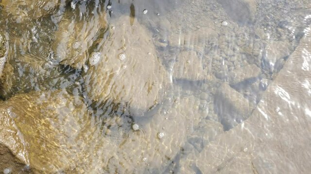 See-through waters of a mountain river streaming calmly over stones, pebbles 