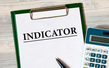 INDICATOR - word on a notebook on a light wooden background with a calculator and a pen