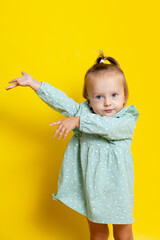 Portrait of a cute baby girl with blue eyes on a yellow background. A place for text.