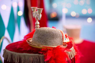 On the velvet tablecloth lies a golden theatrical hat with feathers and a candlestick.