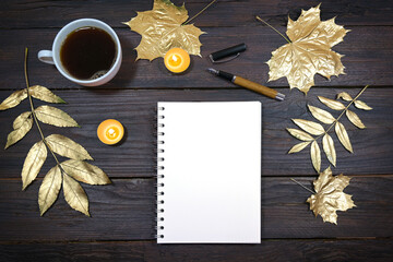 mock up of a blank notebook page on a dark rustic wooden table with coffee, gold colored autumn...