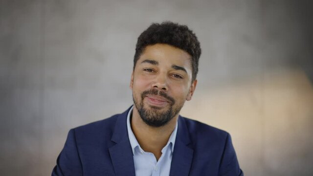 Smiling mixed race man looking at camera and listening. Head and shoulders shot of curly haired mid adult man.