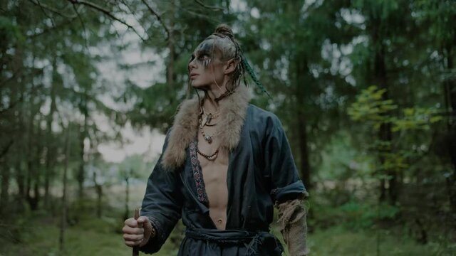 Brave elf wizard with makeup in stylish clothes in forest