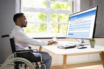 African Man In Wheelchair Filling Online Survey Form