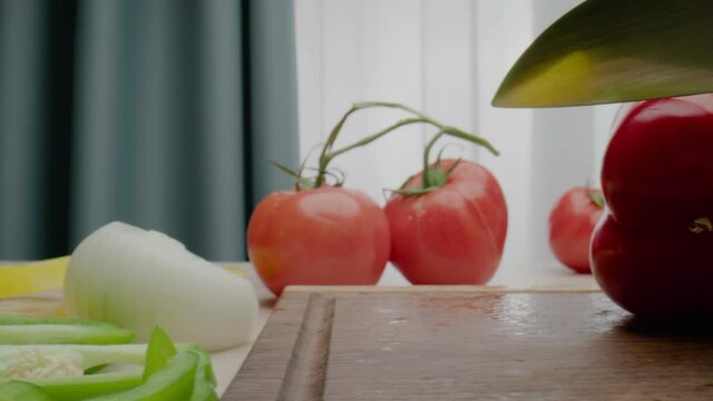 Person cuts off red bell pepper piece with green peduncle