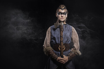 Woman viking warrior in history costume with ax on dark background - 460585123