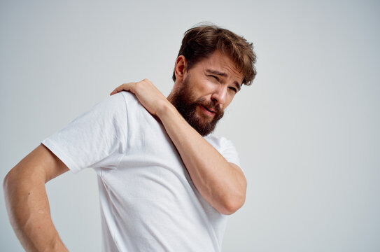 bearded man holding neck arthritis health problems light background