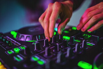 DJ Hands creating and regulating music on dj console mixer in concert nightclub