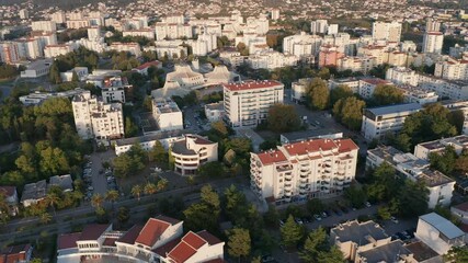 Bar, Montenegro - Aerial drone view of white multistory apartment buildings among trees in residential district of city downtown planned with green urbanism in mind, on sunny morning or afternoon.