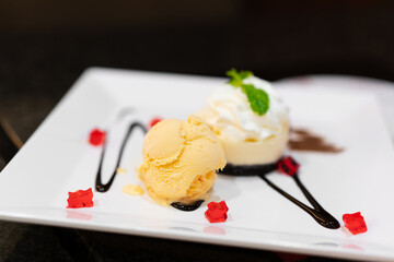 vanilla ice cream with white chocolate mousse cake and red jelly with herb leaf on white dish or plate and black or dark table for sweet dessert or cool snack for food to eat on break and summer