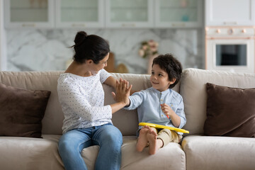 Cheerful asian mixed race two generations family having fun, resting on comfortable sofa. Caring...