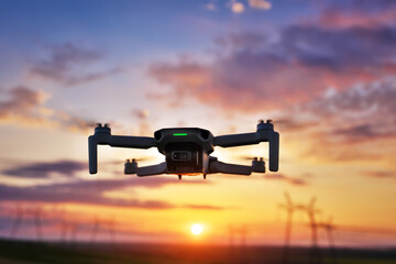 drone quadcopter with digital camera in flight at sunset
